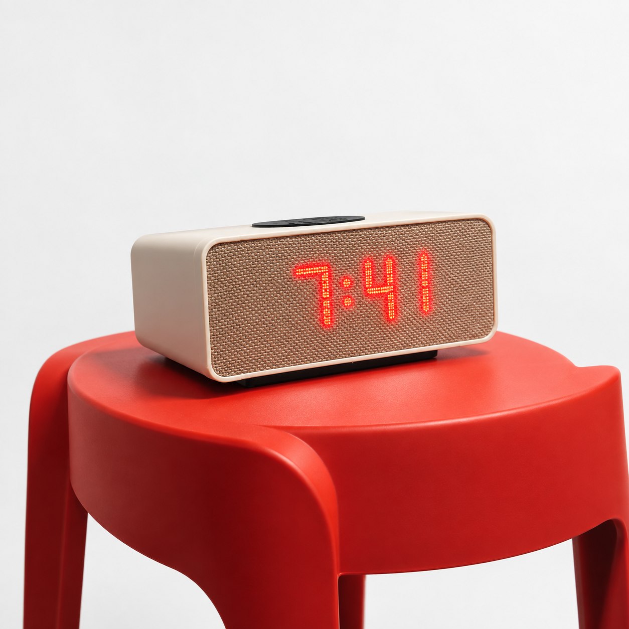 The Aveira One at an angle on a red side table, showing the top dock and volume knob