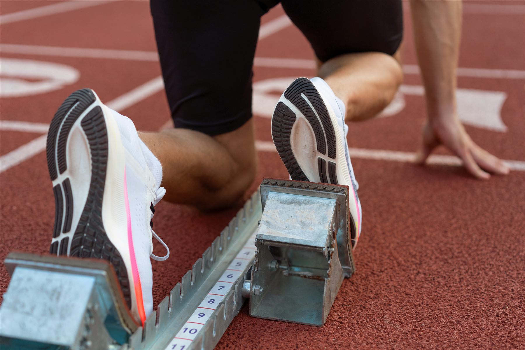 An athlete crouched at the starting blocks on a running track